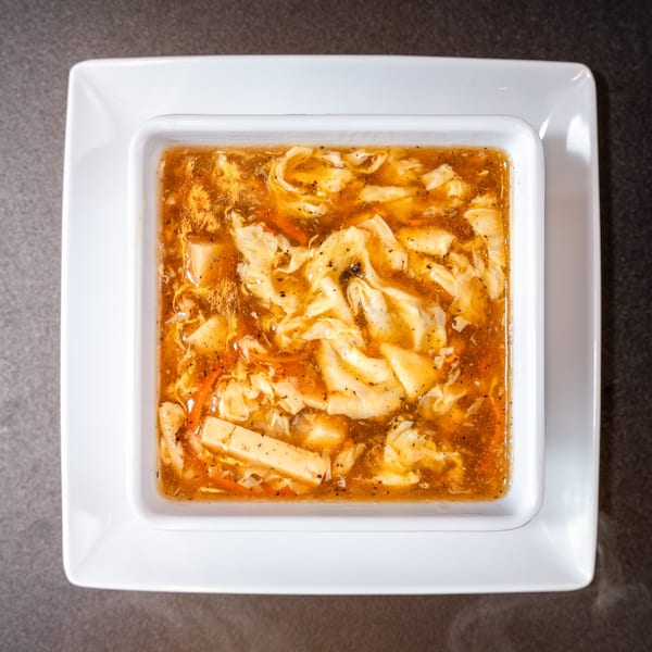 Overhead view of a square white bowl filled with Yen Ching Express hot and sour soup.