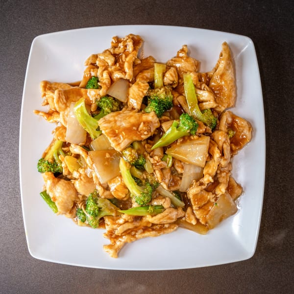 Yen Ching Express's chicken and broccoli stir-fry with onions in a savory brown sauce on a white plate.