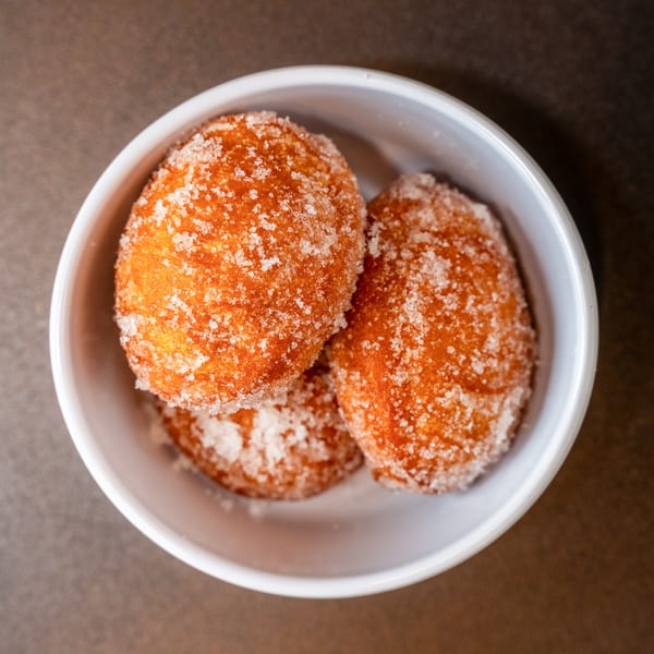 Three golden-brown Chinese donuts, coated in sugar, served in a white bowl.
